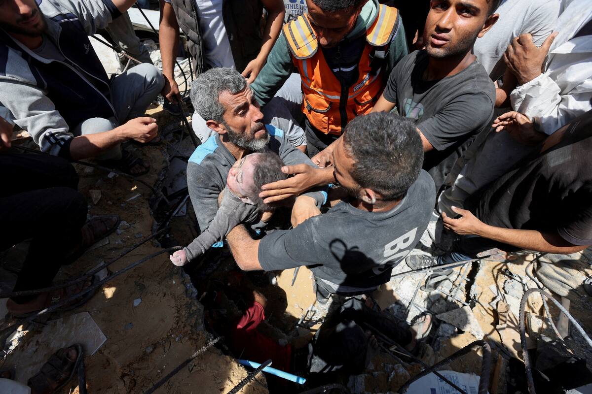  MATERIAL SENSIBLE. ESTA IMAGEN PUEDE OFENDER O MOLESTAR Palestinos transportan el cadáver de un niño recuperado de entre los escombros de una casa alcanzada por un ataque israelí, en medio del actual conflicto entre Israel y el grupo islamista palestino Hamás, en el campo de refugiados de Nuseirat, en el centro de la Franja de Gaza, 14 de mayo de 2024. REUTERS/Ramadan Abed