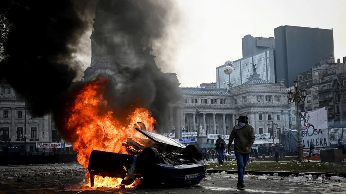 Manifestantes incendian un carro durante protestas por la ley Omníbus. | REUTERS