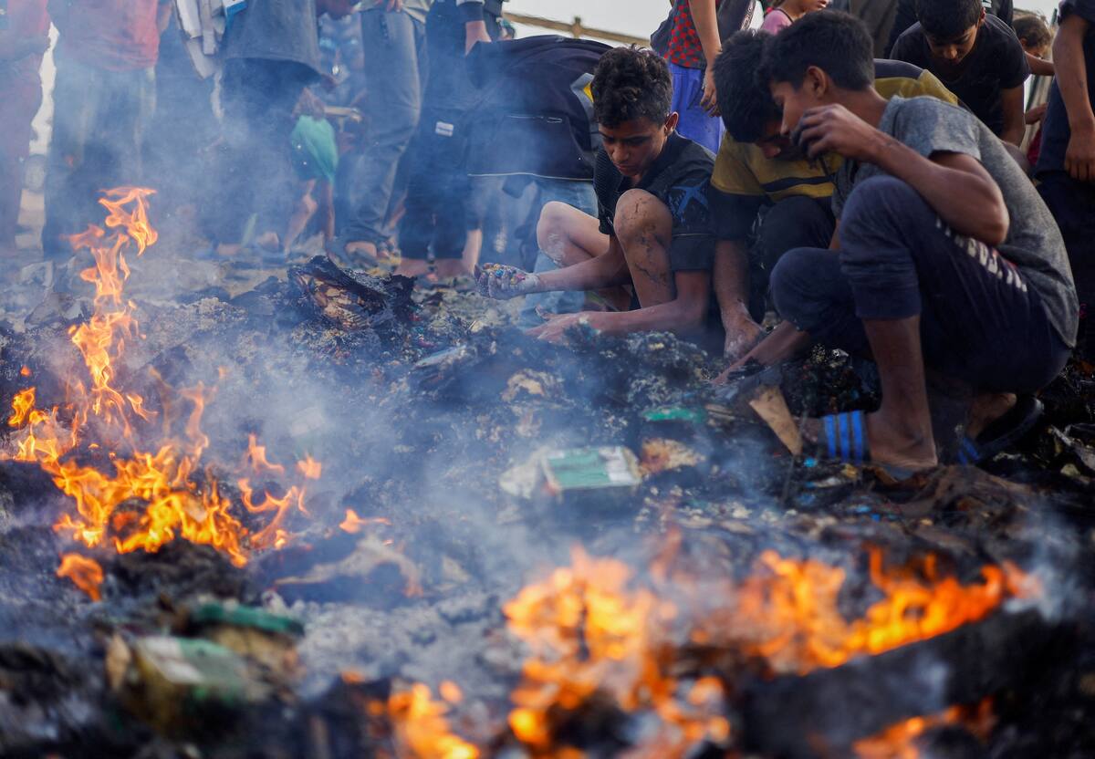 Los palestinos buscan comida entre escombros quemados tras un ataque israelí contra una zona designada para personas desplazadas, en Rafah, en el sur de la Franja de Gaza, el 27 de mayo de 2024. REUTERS/Mohammed Salem