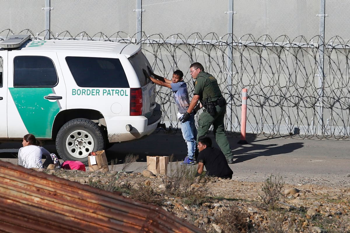 ARCHIVO - En esta fotografía del 15 de diciembre de 2018, unos solicitantes de asilo hondureños son detenidos por los agentes de la Patrulla Fronteriza de Estados Unidos, tras cruzar el muro fronterizo de Tijuana, México, a San Diego, California. (AP Foto/Moises Castillo, Archivo)